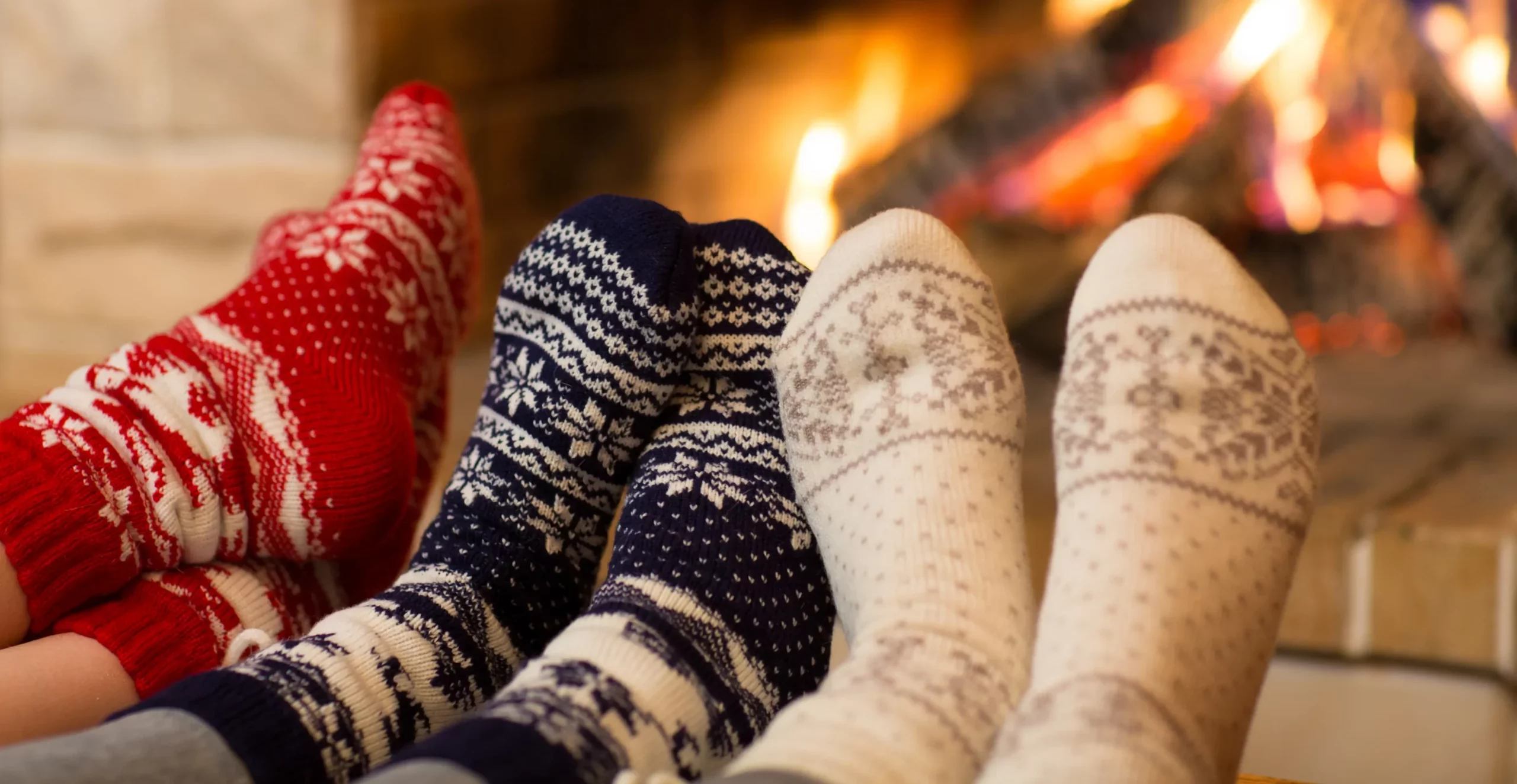 two people keeping their feet warm next to the fireplace.