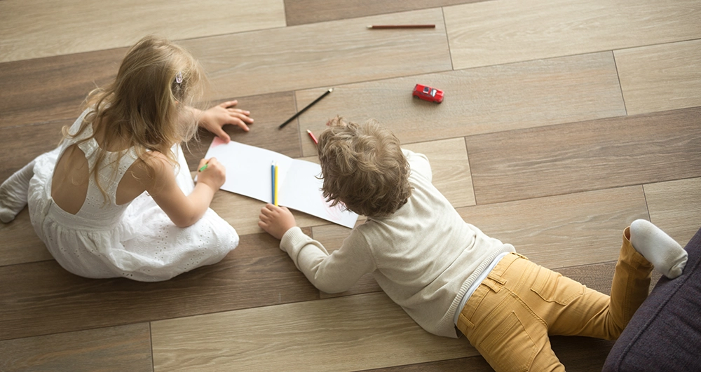 brother and sister drawing on a warm floor